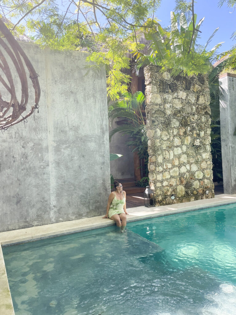A woman soaking her feet in the pool at Casa Hormiga Bacalar.